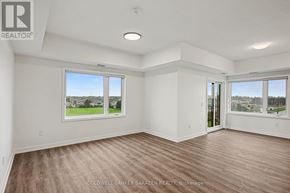 Arnprior condo for rent - A spacious room with wooden flooring and large windows overlooking a green landscape.