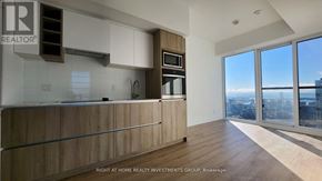 Toronto (Moss Park) condo for rent - A modern kitchen with wooden cabinets and a large window overlooking the city.
