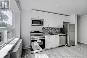Toronto (The Beaches) condo for rent - A modern kitchen with stainless steel appliances and white cabinets.