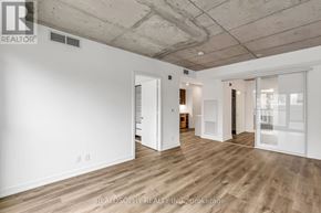 Toronto (South Riverdale) condo for rent - A room with a white wall and a wooden floor.