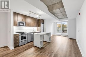Toronto (South Riverdale) condo for rent - A spacious kitchen with wooden cabinets and stainless steel appliances.