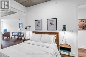 Toronto (South Riverdale) condo for rent - A bedroom with a large bed, a table with a lamp, and two framed pictures on the wall.