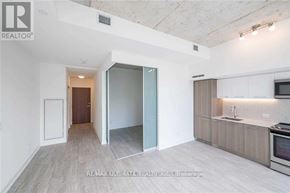Toronto (South Riverdale) condo for rent - A spacious room with a kitchen area and a doorway leading to another room.