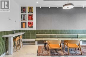 Toronto (South Riverdale) condo for rent - A room with a green couch, a white table, and a wall with pictures on it.