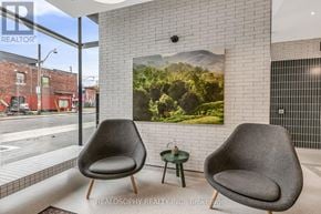 Toronto (South Riverdale) condo for rent - Two grey chairs are placed in a room with a large poster on the wall.