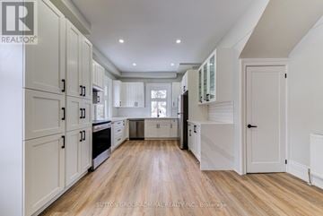 Barrie (North Shore) multi-family for rent - A spacious kitchen with white cabinets and wooden flooring.