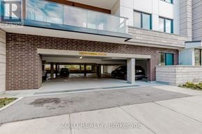 Oakville (Co Central) condo for rent - A modern building with a garage entrance and a car parked inside.