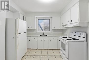 Toronto (Mimico) multi-family for rent - A white kitchen with a refrigerator, stove, and cabinets.