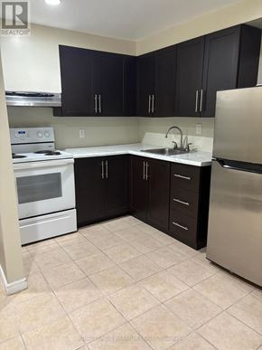 Toronto (Weston-Pellam Park) multi-family for rent - A kitchen with black cabinets and stainless steel appliances.