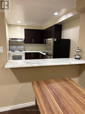 Toronto (Weston-Pellam Park) multi-family for rent - A kitchen with a black refrigerator and wooden countertop.