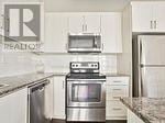 Toronto (Long Branch) townhouse for rent - A kitchen with a stove top oven and a microwave above it.