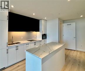 Kitchener condo for rent - A modern kitchen with white cabinets and a central island.