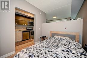 Waterloo condo for rent - A bedroom with a patterned bedspread and a small bedside table.
