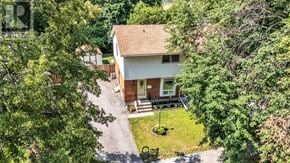 London East (East D) apartment for rent - A house with a brown roof and a white garage door is surrounded by trees.