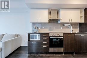Toronto (Mount Pleasant West) condo for rent - A modern kitchen with dark wood cabinets and stainless steel appliances.