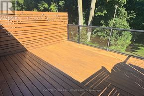 Toronto (Mount Pleasant East) duplex for rent - A wooden deck with a railing and trees in the background.