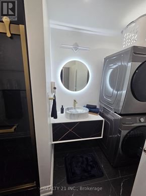 Toronto (Rouge) apartment for rent - A modern bathroom with a round mirror and a washing machine built into the cabinet.