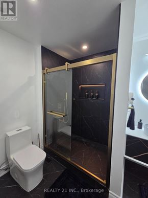 Toronto (Rouge) apartment for rent - A white toilet sits in a bathroom with a marble floor and gold trim.