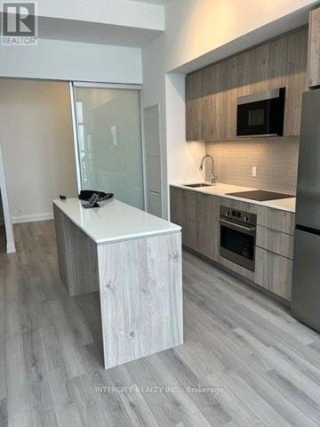 Brampton (Bram East) condo for rent - A modern kitchen with a white island and wooden cabinets.
