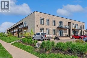 Brantford condo for rent - A modern building with a parking lot in front.