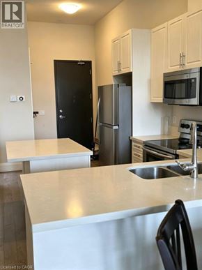 Brantford condo for rent - A kitchen with a sink, refrigerator, and microwave.