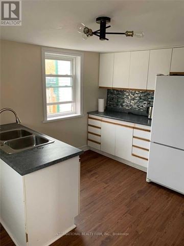 Cobourg apartment for rent - A kitchen with white cabinets and a black countertop.
