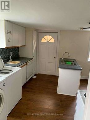 Cobourg apartment for rent - A kitchen with white cabinets and a wooden floor.
