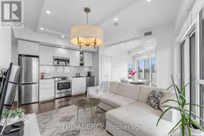 Toronto (Niagara) condo for rent - A modern kitchen with a white color scheme and a dining area with a white couch.