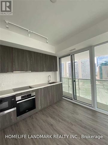 Toronto (Waterfront Communities) condo for rent - A kitchen with wooden cabinets and a microwave.