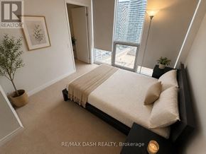 Toronto (Church-Yonge Corridor) condo for rent - A bedroom with a large bed and a view of the city.
