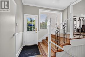 Ottawa apartment for rent - A hallway with a white door and a staircase with a black railing.
