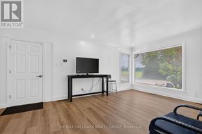 Ottawa apartment for rent - A room with a TV on a stand and a window showing a view of a yard.