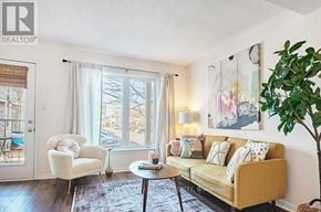 Ottawa townhouse for rent - A living room with a yellow couch, a white chair, and a painting on the wall.