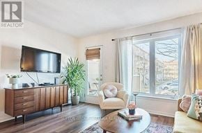 Ottawa townhouse for rent - A living room with a flat screen TV, a chair, a plant, and a coffee table.