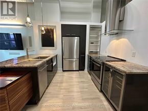 Toronto (Niagara) condo for rent - A modern kitchen with a black fridge and wooden cabinets.