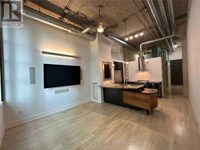 Toronto (Niagara) condo for rent - A spacious room with a flat screen TV mounted on the wall and a wooden cabinet with a countertop.