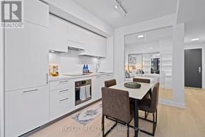 Toronto (Thorncliffe Park) condo for rent - A modern kitchen with white cabinets and a dining table with chairs.