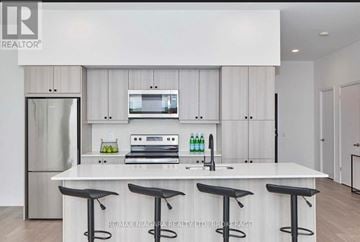 Niagara Falls (Oldfield) condo for rent - A modern kitchen with white cabinets and a central island with a bar stool.