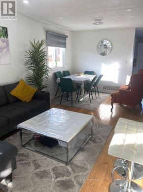 Brampton (Sandringham-Wellington) apartment for rent - A living room with a grey couch, a glass coffee table, and a dining table with chairs.