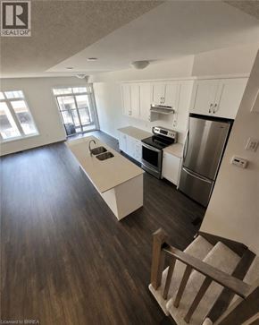 Brantford townhouse for rent - A modern kitchen with dark wood floors and stainless steel appliances.
