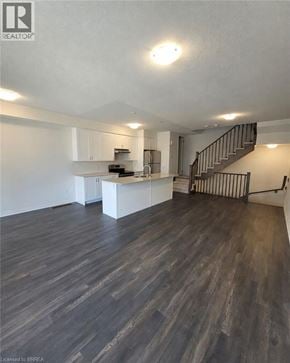 Brantford townhouse for rent - A spacious kitchen and living room with wood flooring and a staircase.