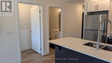 Hamilton condo for rent - A kitchen with a refrigerator, sink and cabinets.