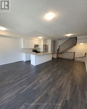 Brantford townhouse for rent - A spacious kitchen and living room with wood flooring and a staircase.
