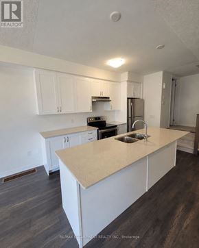 Brantford townhouse for rent - A kitchen with white cabinets and a beige island.