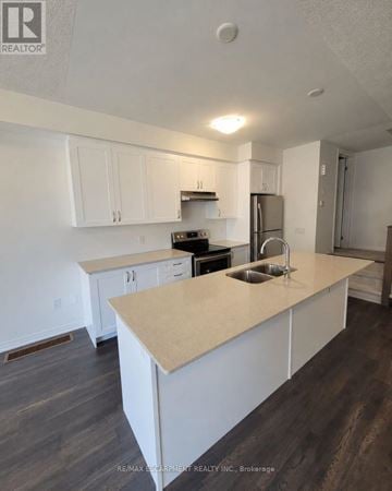 Brantford townhouse for rent - A kitchen with white cabinets and a beige island.