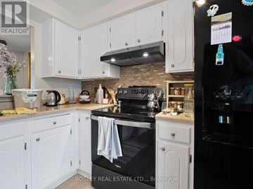 Niagara Falls (Stamford) townhouse for rent - A kitchen with white cabinets and a black stove.