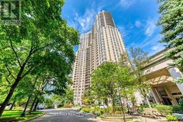 Mississauga (Hurontario) condo for rent - A tall residential building is surrounded by trees and greenery.
