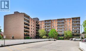 Kitchener condo for rent - A parking lot in front of a multi-story apartment building.