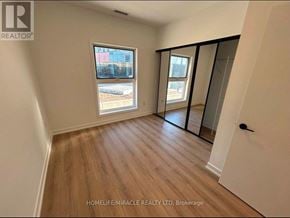 Brampton (Northwest Brampton) condo for rent - A room with wooden flooring and a large window overlooking a construction site.