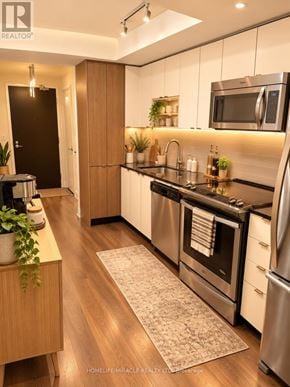 Toronto (Islington-City Centre West) condo for rent - A modern kitchen with wooden floors and stainless steel appliances.